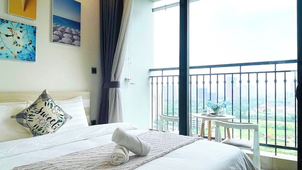 A hotel room with a bed, a small table with a view, and a balcony with a railing. - G3- Green Bay (Hanoi)