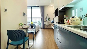 A modern kitchen with a dining area, a small table with chairs, and a view through a window. - G3- Green Bay (Hanoi)