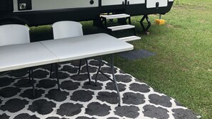 Een recreatiewagen met een tafel en stoelen op een kamerkleed met patroon.