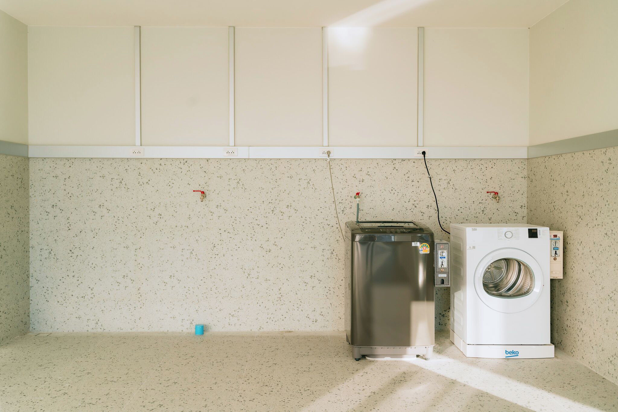 A laundry room with a stainless steel dryer and a white front-loading washing machine.