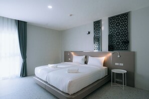 A modern hotel room with a large bed, bedside tables, a small round table, and decorative wall panels. - One Budget Hotel Chiangrai Bypass-East (Chiang Rai)
