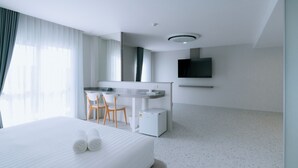 Une chambre d’hôtel équipée d’un lit, d’un bureau, d’une chaise, d’une télévision et d’un petit réfrigérateur.