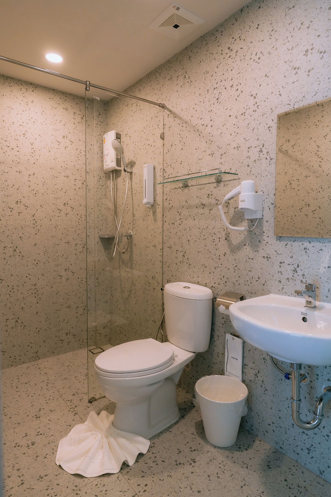 Une salle de bain comprenant des toilettes, un bidet, un lavabo et une douche.