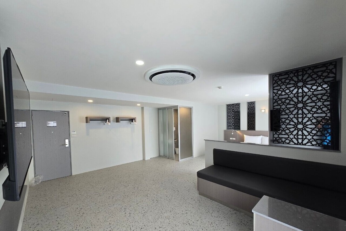Un vestíbulo moderno con piso moteado, mostrador de recepción, escalera y un panel decorativo en la pared.