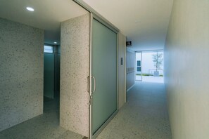 Un pasillo con una puerta de vidrio esmerilado, un picaporte de metal y un cartel que indica zona de taquillas.