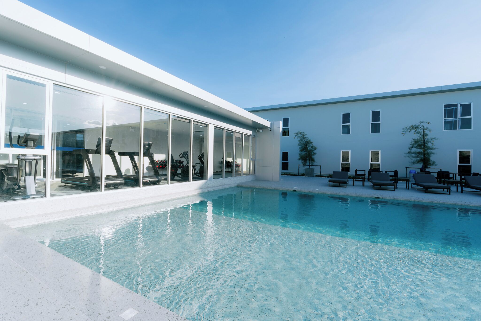 Un edificio moderno con piscina, equipo de gimnasia y sillones de descanso.