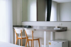 A modern hotel room with a large mirror, a small desk, two chairs, and a compact washing machine. - One Budget Hotel Chiangrai Bypass-East (Chiang Rai)