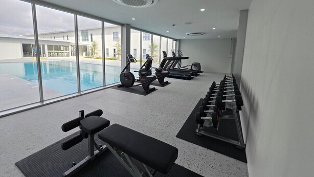 Une salle de sport équipée de rameurs, de tapis de course et d’haltères, avec vue sur une piscine.