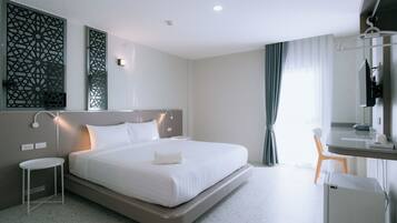 Quarto de hotel moderno com uma cama grande, mesas de cabeceira, uma escrivaninha com cadeira e televisão.