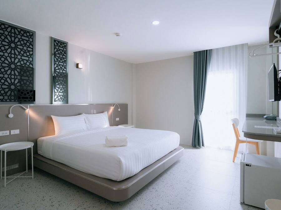Quarto de hotel moderno com uma cama grande, mesas de cabeceira, uma escrivaninha com cadeira e televisão.