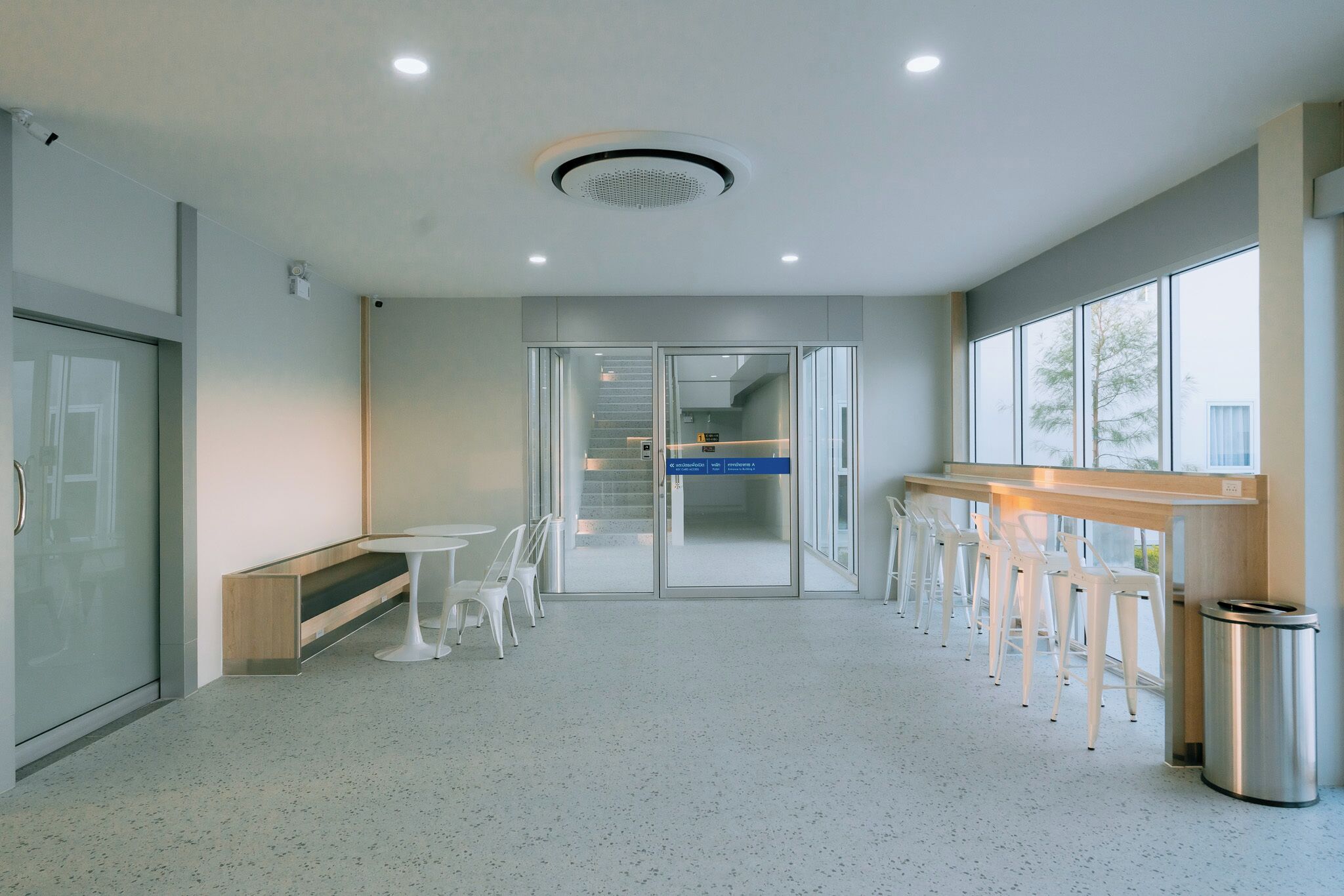 A modern interior with a seating area, a staircase, and a trash bin.
