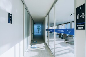 A hallway leading to fitness rooms with clear signage, a glass door, and a view of outdoor exercise equipment. - One Budget Hotel Chiangrai Bypass-East (Chiang Rai)