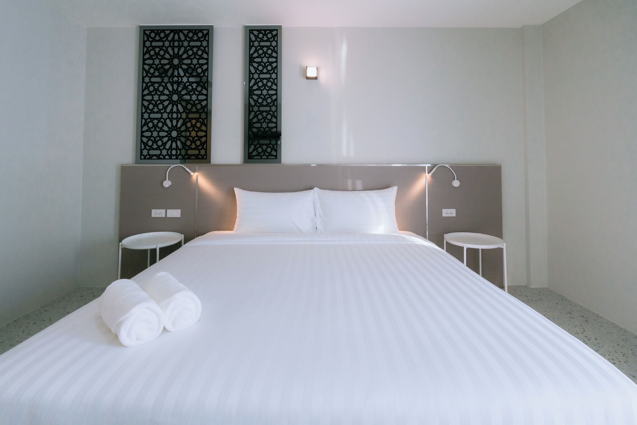 Een hotelkamer met een groot bed, twee nachtkastjes en decoratieve wandpanelen.