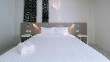 Een hotelkamer met een groot bed, twee nachtkastjes en decoratieve wandpanelen.