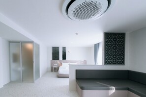Une chambre d’hôtel moderne équipée d’une kitchenette, d’un lit, d’un coin salon et d’un panneau décoratif mural.