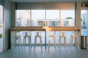 A modern kitchen with a large window, a wooden countertop, and five white bar stools. - One Budget Hotel Chiangrai Bypass-East (Chiang Rai)