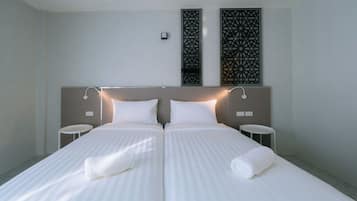 A double bed with two pillows, a bedside table on each side, and a decorative wall panel above.