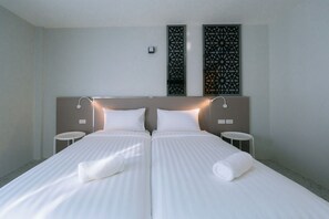 A double bed with two pillows, a bedside table on each side, and a decorative wall panel above. - One Budget Hotel Chiangrai Bypass-East (Chiang Rai)
