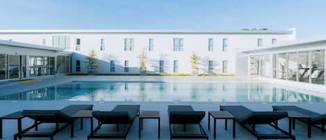 A modern building with a swimming pool, sun loungers, and exercise equipment.