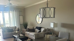 A dining area with a dark wooden table and grey upholstered chairs, a ceiling fan, and a decorative light fixture.