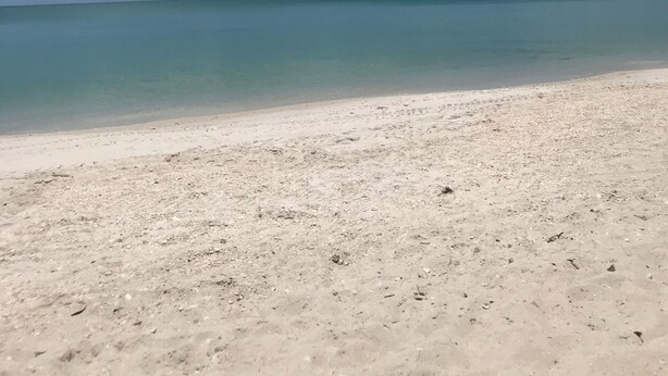 A beach with clear blue water and white sand.