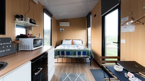 Una habitación compacta con cama, una kitchenette pequeña, una ventana y vistas al exterior.