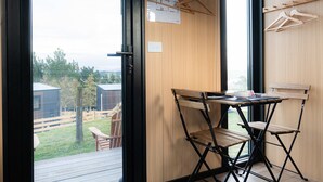 Una habitación con una mesa de madera, dos sillas y vistas al exterior.