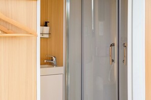 Ein modernes Badezimmer mit Duschkabine aus Glas, einem Holzwaschtisch und einem weißen Waschbecken.