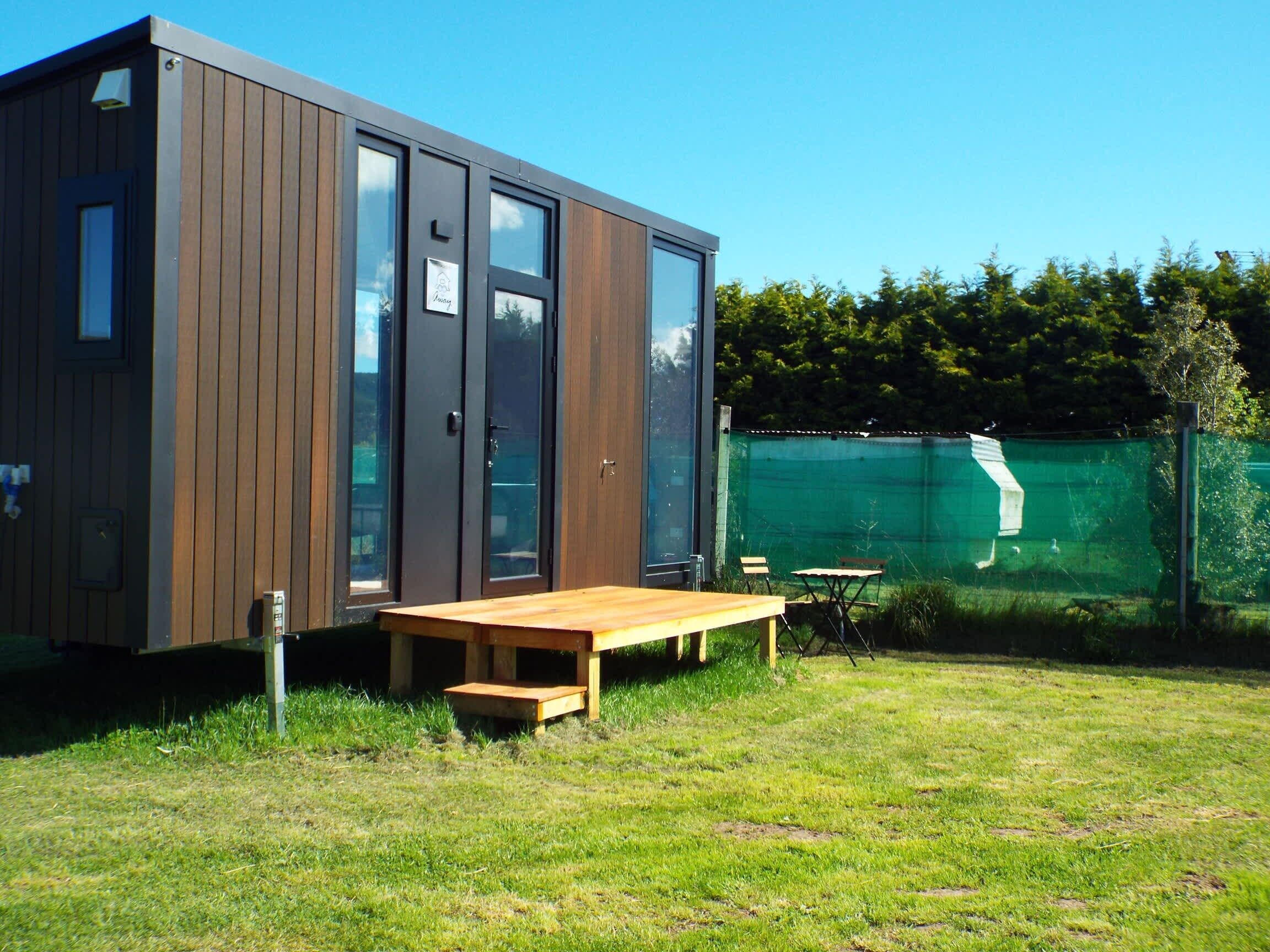 A modern wooden cabin with large windows and a wooden deck.