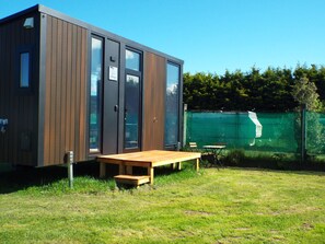 Een moderne houten hut met grote ramen en een houten terras.