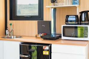 Een keuken met een vaatwasser, een magnetron, een koffiezetapparaat en een raam met uitzicht op het platteland.