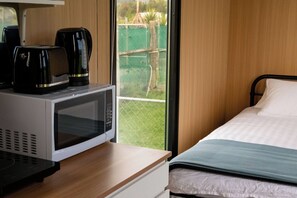 Een hotelkamer met een bed, een magnetron en een koffiezetapparaat op een houten tafel.