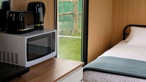 Une chambre d’hôtel avec un lit, un four à micro-ondes et une machine à café, le tout posé sur une table en bois.