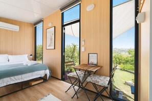 A bedroom with a bed, a desk, and a view of the outdoors. - Kanimbla Sunsets by Tiny Away (Kanimbla)