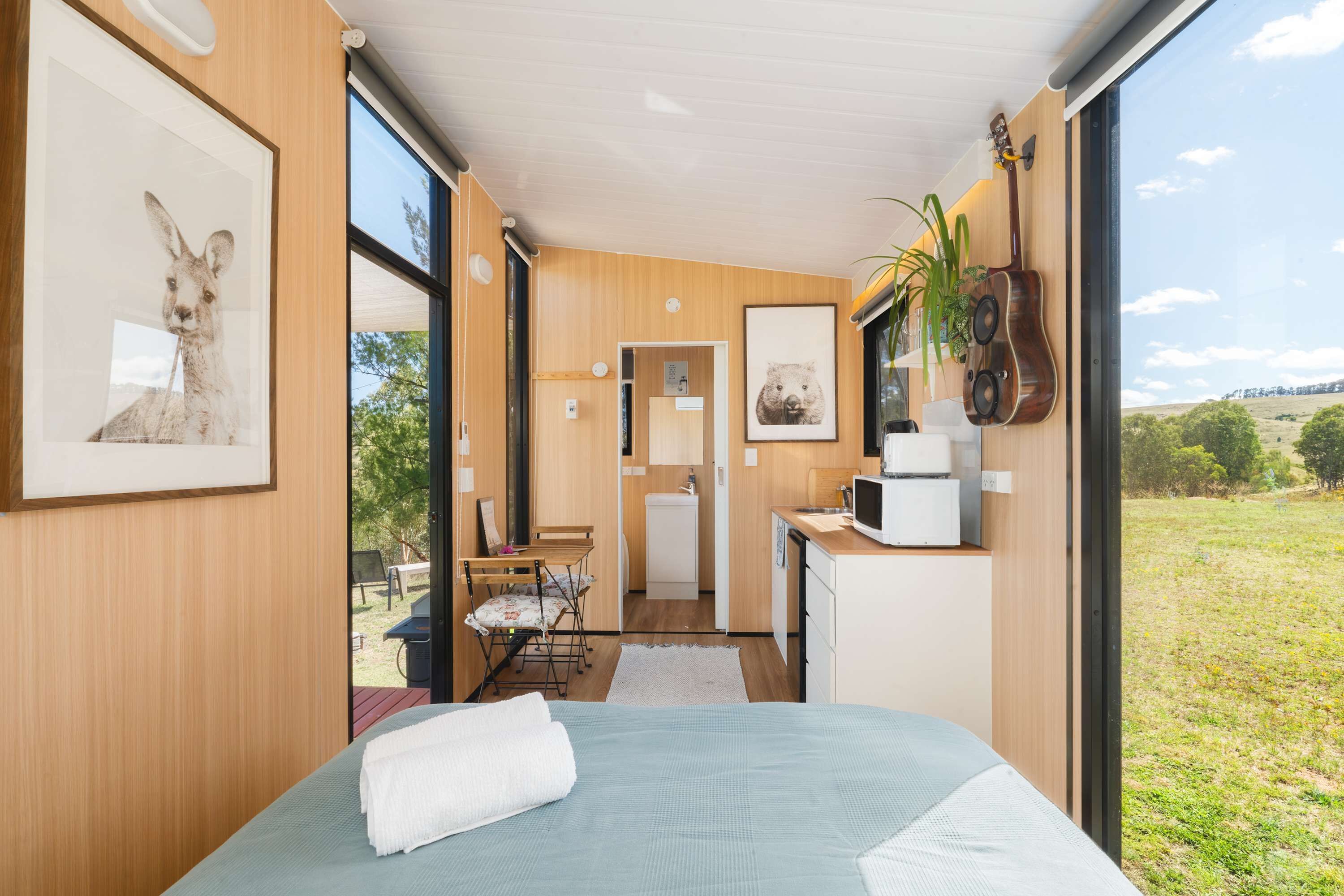 Un dormitorio moderno con una cama grande, una kitchenette pequeña y vistas al exterior.