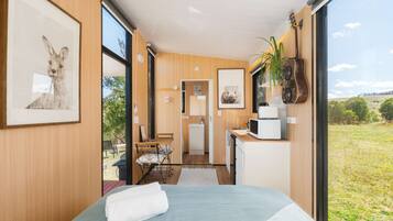 Un dormitorio moderno con una cama grande, una kitchenette pequeña y vistas al exterior.