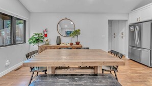 A modern kitchen with a wooden dining table, white cabinets, and a stainless steel refrigerator. - Bright Tahoe Home w/ Private Backyard, Near Beach (Tahoe City)