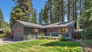 A two-story house with a red garage door, a covered porch, and a well-maintained lawn. - Bright Tahoe Home w/ Private Backyard, Near Beach (Tahoe City)