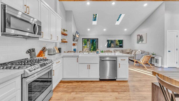 A modern kitchen with white cabinets, stainless steel appliances, and a wooden ceiling. - Bright Tahoe Home w/ Private Backyard, Near Beach (Tahoe City)