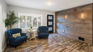 A room with a dark blue armchair, a small round table, and a potted plant. - The Mile High Haven: An Entertainers Dream Home with Hot Tub + Perfect Location (Lakewood)