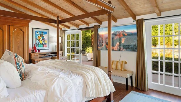 A bedroom with a four-poster bed, a large window with a view, and a painting on the wall. - Villa Sol: Private Las Palmas Estate Home (Palm Springs)
