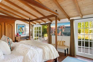 Une chambre à coucher avec un lit à baldaquin, une grande fenêtre donnant sur un beau paysage et un tableau accroché au mur.