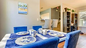 A dining area with a table set for four, blue upholstered chairs, and a painting on the wall. - Spacious 3BR Two-Story Home Near Downtown Jax (Jacksonville)