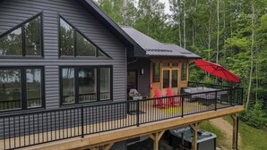 A modern house with a large deck, a hot tub, and a covered patio area.