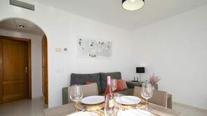 A dining area with a table set for four, a sofa, and a painting on the wall. - Imperial Park by Interhome (Calpe/Calp)