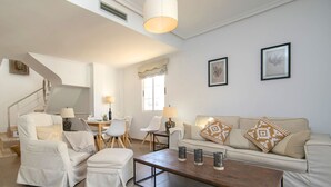 Ein geräumiges Wohnzimmer mit einer Couch, Sesseln, einem Couchtisch und einem Essbereich mit Stühlen und Tisch.