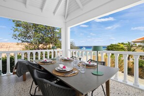 A covered outdoor dining area with a table set for four, overlooking a scenic coastal view. - Kas Chiki , Charming, Stylish Seaside escape,  just steps from the Caribbean Sea (Kralendijk)