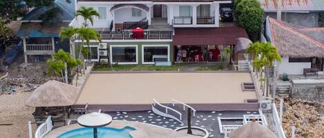 A resort with a swimming pool, lounge chairs, and a covered deck area.