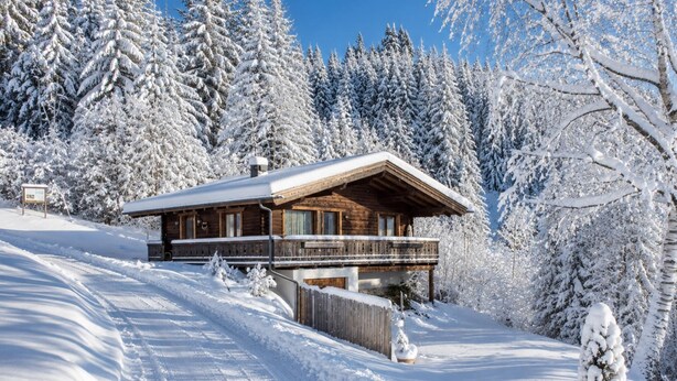 Eine Holzdiele mit Balkon, umgeben von schneebedeckten Bäumen.