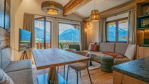 Ein modernes Interieur mit einem Holzespeisetisch, Sitzgelegenheiten und großen Fenstern mit Blick auf die Berge.